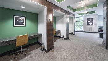 A hallway with a green wall and a desk with a chair